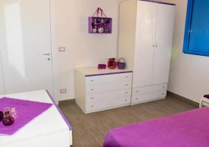 a bedroom with a bed and a dresser with purple sheets at Casa Vacanze Portopalo di Capopassero in Portopalo