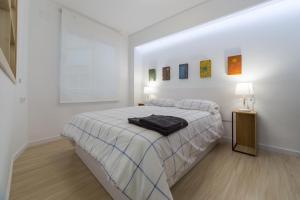 ein weißes Schlafzimmer mit einem Bett und einem schwarzen Handtuch darauf in der Unterkunft Valencia Just in the Middle in Valencia