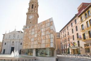 a building with a clock tower next to a fountain at Hotel Tibur in Zaragoza