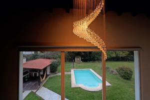 una lámpara de araña colgando sobre una ventana junto a una piscina en Hermosa Casa con Pileta Roldán Funes Rosario en Roldán