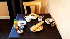 una mesa con pan, café y bebidas. en Hotel de La Paix, en Oloron-Sainte-Marie