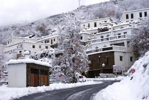 una calle cubierta de nieve en una ciudad con edificios en Casa De La Ermita, en Bubión
