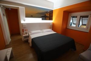 a bedroom with a bed with orange walls and a window at Hotel Fiume in Genoa