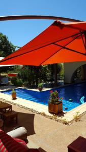 un grande ombrellone rosso sopra una piscina di L'échappée belle Benslimane a Ben Slimane