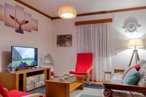 a living room with a television and a red chair at Casa do Pequeno Dragoeiro in Angra do Heroísmo