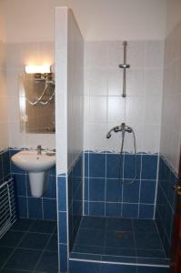 y baño azul y blanco con lavabo y ducha. en Villa Patio en Patince
