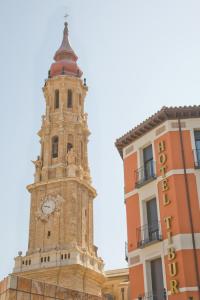 una torre con un reloj al lado de un edificio en Hotel Tibur, en Zaragoza