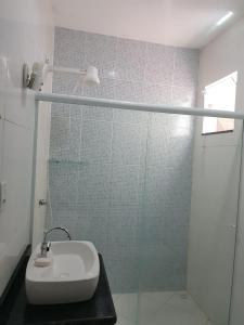y baño con lavabo y ducha acristalada. en Brilho do Sol Hospedagem, en Arraial do Cabo