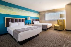 a hotel room with two beds and a chair at Downtown Grand Hotel & Casino in Las Vegas