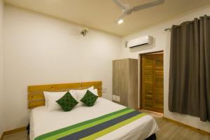 a bedroom with a bed with white sheets and green pillows at Holiday Garden Rasdhoo in Rasdhoo