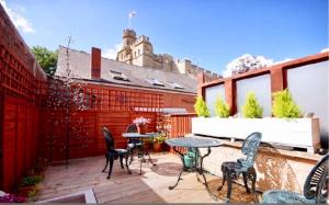 eine Terrasse mit Tischen und Stühlen auf einem Gebäude in der Unterkunft Castle View Cottage in Lincoln