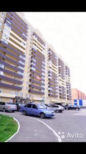 a parking lot with cars parked in front of a large building at Yasmina in Maykop