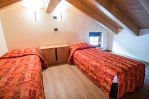 Habitación con 2 camas y suelo de madera. en Miky House - Appartamenti Abar, en Livigno
