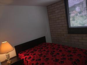 a bedroom with a bed with a red blanket and a lamp at Apartamento relajante , exclusivo, moderno e iluminado ,Sabaneta ,Medellín in Sabaneta