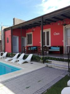 a group of white chairs next to a red building at Carmine Hotel Apart in Capilla del Señor
