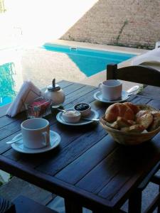 una mesa de madera con tazas de café y un tazón de pan en Carmine Hotel Apart en Capilla del Señor