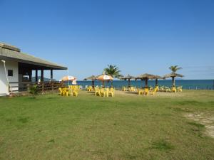 un grupo de mesas y sombrillas amarillas en la playa en ACIOLY'S BEACH HOUSE, en Caraguatatuba