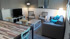 sala de estar con sillas, mesa y TV en la maison du postier, en Port-en-Bessin-Huppain