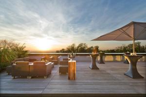 eine Terrasse mit Stühlen und einem Sonnenschirm bei Sonnenuntergang in der Unterkunft Lufthansa Seeheim - More than a Conference Hotel in Seeheim-Jugenheim