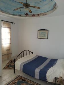 sypialnia z łóżkiem i wentylatorem sufitowym w obiekcie Maison les Palmiers 300m de la plage w mieście Aghīr