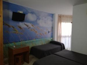 a bedroom with two beds and a wall with a mural at Hostal Maribel in Almería