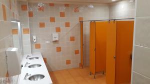 - Baño con 2 lavabos y puestos de color naranja en Area de servicio El Rebollar, en Requena