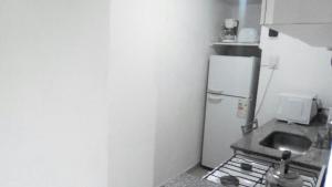 una pequeña cocina con fogones y nevera. en Departamento de Jerarquía en Recoleta en Buenos Aires