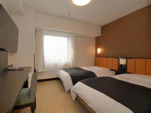 a hotel room with two beds and a window at APA Hotel Gifu Hashima Ekimae in Hashima