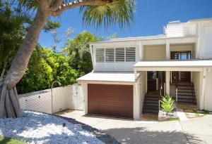 een wit huis met een garage en een palmboom bij 1-18 Stevens Street, Sunshine Beach in Noosa Heads