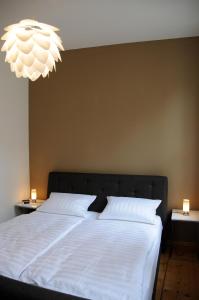 Schlafzimmer mit einem Bett mit weißer Bettwäsche und einem Kronleuchter in der Unterkunft Apartments am Brunnen in Quedlinburg