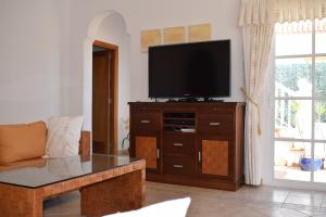 a living room with a television on a wooden entertainment center at Villa Rochelle in Caleta De Fuste