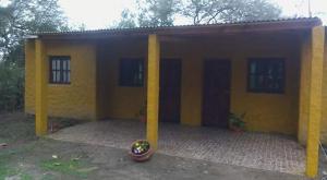 uma casa amarela com duas colunas à frente em Cabañas del Dique em Termas de Rio Hondo