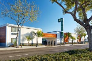 ein Gebäude in einer Straße mit Palmen in der Unterkunft Studio Inn & Suites at Promenade Downey in Downey