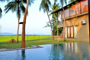 a swimming pool in front of a building with palm trees at Kethaka Aga in Tissamaharama