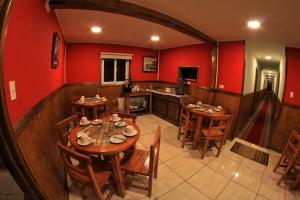 a dining room with red walls and wooden tables and chairs at Hostal America en Puerto Natales in Puerto Natales
