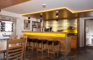 ein Restaurant mit einer Bar mit gelber Theke und Stühlen in der Unterkunft Gasthof Venetrast in Imsterberg