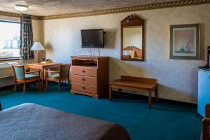 Habitación de hotel con cama, escritorio y TV. en Guest House Inn, en Junction City
