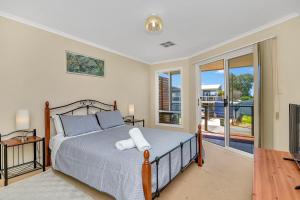 a bedroom with a bed and a balcony at Green Reef Beach House in Aldinga Beach