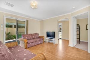 a living room with a couch and a tv at Green Reef Beach House in Aldinga Beach