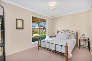 um quarto com uma cama e uma janela em Green Reef Beach House - Aldinga Beach - C21 SouthCoast Holidays em Aldinga Beach