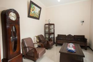 瑪琅的住宿－RedDoorz At Omah Wetan Sawojajar Malang，客厅配有祖父钟和椅子