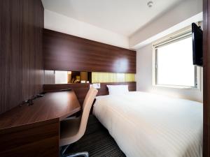 a bedroom with a bed and a desk and a window at Super Hotel Izumo Ekimae in Izumo