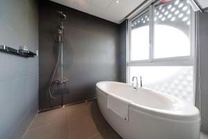 a white bath tub in a bathroom with a window at Hotelpoispois in Taipei