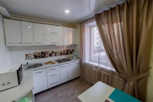 a small kitchen with white cabinets and a window at Квартира in Temirtaū