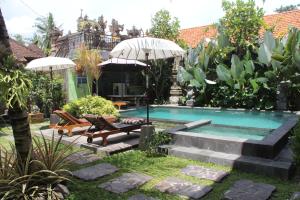 a backyard with a swimming pool with chairs and umbrellas at Villa Bungsil Gading in Ubud