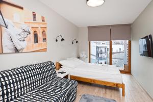 a bedroom with a bed and a couch and a window at Apartamenty Sun & Snow Olimp Apartments in Krakow