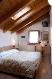a bedroom with a large bed and wooden ceilings at Albergo Ristorante Alle Codole in Canale dʼAgordo