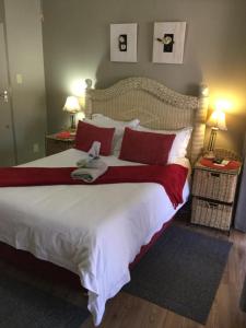 a bedroom with a large bed with red and white pillows at Sanyati Guesthouse in Kathu