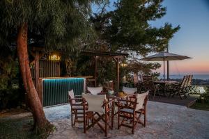 een tafel met stoelen en een parasol op een patio bij Villa Sunrise Lagonisi in Lagonissi