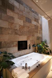 uma banheira na casa de banho com uma televisão na parede em I DO Motel em Taoyuan